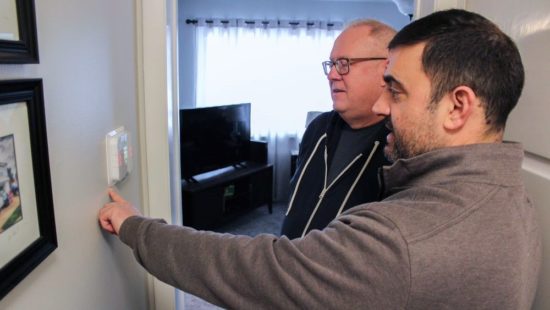 Sales person showing customer how to use their new smart thermostat