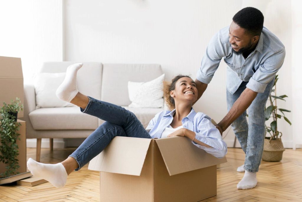Young couple having fun unpacking boxes in new home