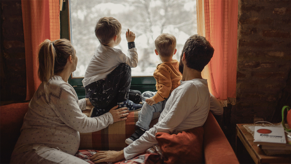 family comfortable sitting by window looking outside with Guardian Alarm home automation keeping them safe and warm