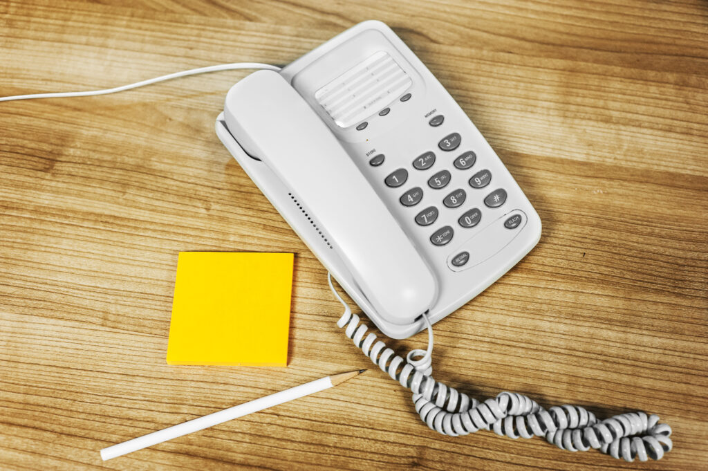 landline telephone with sticky pad and pen