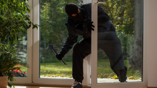 Burglar breaking into a house through a door